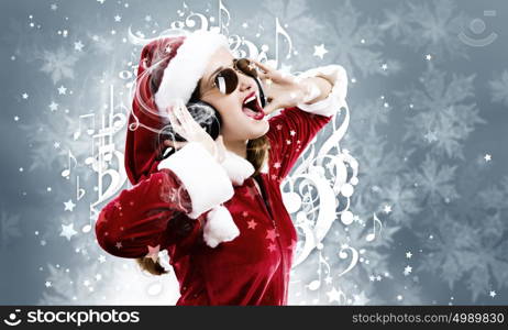 Celebrating New Year. Young attractive Santa girl listening music in headphones