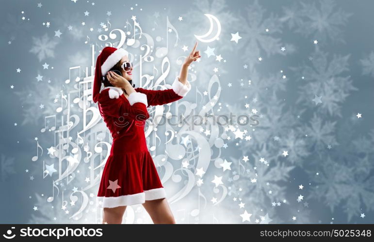 Celebrating New Year. Young attractive Santa girl listening music in headphones