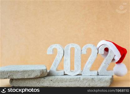 Celebrating the new year 2022. Number 2022 in concrete numerals with santa hat on concrete podiums.