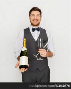celebration, alcohol and holidays concept - happy man or waiter holding bottle of champagne and wine glasses at party. man with bottle of champagne and glasses at party