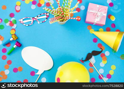 celebration and decoration concept - pink birthday gift, party props, balloons and colorful confetti on blue background. pink birthday gift and party props