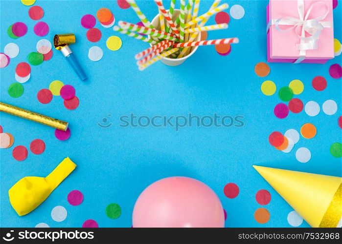 celebration and decoration concept - pink birthday gift, party props, balloons and colorful confetti on blue background. pink birthday gift and party props