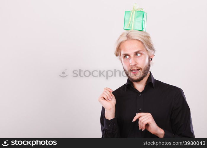 Celebration and giving concept. Cool young man with green gift box on his head. Guy thinking looking for present idea. Thinking guy with green gift box on his head