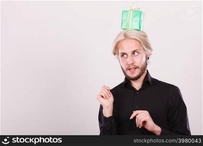 Celebration and giving concept. Cool young man with green gift box on his head. Guy thinking looking for present idea. Thinking guy with green gift box on his head