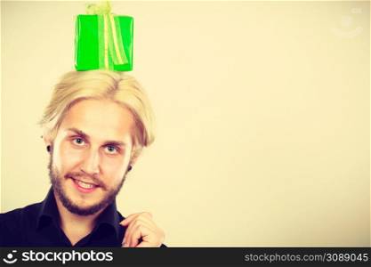 Celebration and happiness concept. Cool happy young man with green gift box on his head. Guy have crazy idea for present. man with green gift box on his head