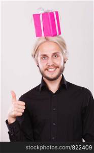 Celebration and happiness concept. Cool happy young man with pink gift box on his head. Guy have crazy idea for present. man with pink gift box on his head