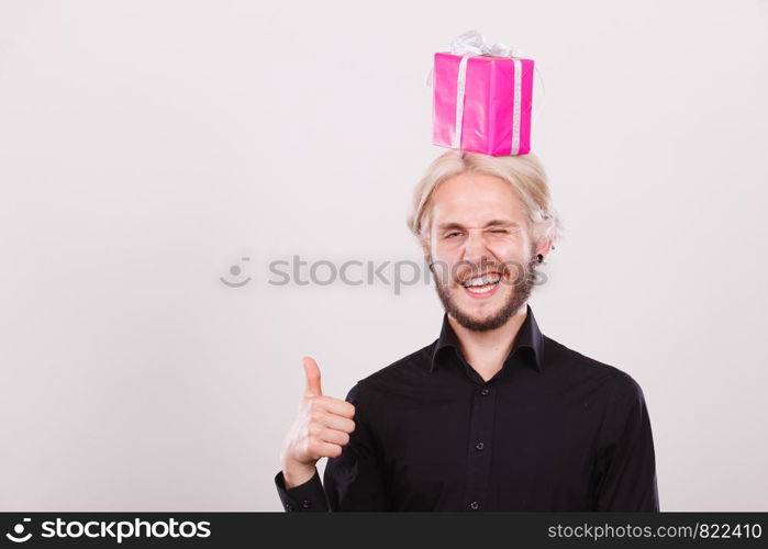 Celebration and happiness concept. Cool happy young man with pink gift box on his head. Guy have crazy idea for present. man with pink gift box on his head