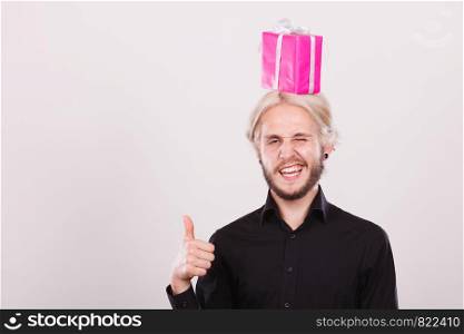 Celebration and happiness concept. Cool happy young man with pink gift box on his head. Guy have crazy idea for present. man with pink gift box on his head