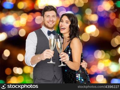 celebration and holidays concept - happy couple with glasses drinking non alcoholic champagne at party over lights background. happy couple with champagne glasses at party. happy couple with champagne glasses at party