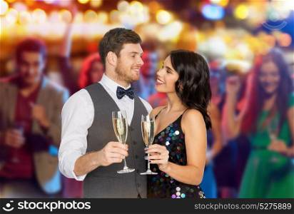 celebration and holidays concept - happy couple with glasses drinking non alcoholic champagne at party over night club lights background. happy couple with champagne glasses at party