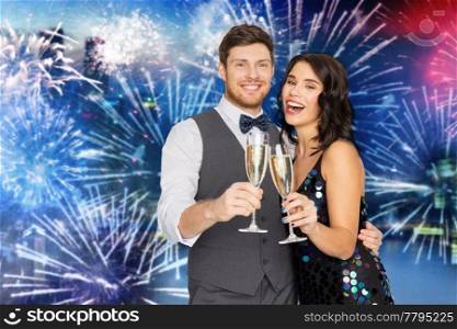 celebration and holidays concept - happy couple with glasses drinking non alcoholic champagne at party over firework background. happy couple with champagne glasses at party