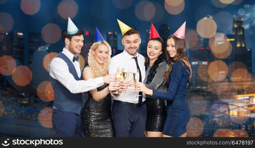 celebration and holidays concept - happy friends clinking champagne glasses at birthday party over night singapore city and lights background. friends with champagne glasses at birthday party. friends with champagne glasses at birthday party