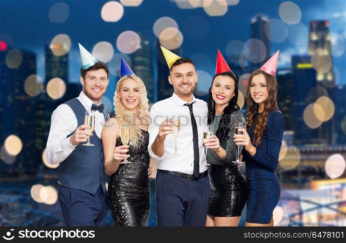 celebration and holidays concept - happy friends with champagne glasses at birthday party over night singapore city lights background. friends with champagne glasses at birthday party. friends with champagne glasses at birthday party