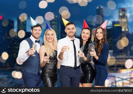 celebration and holidays concept - happy friends with champagne glasses at birthday party over night singapore city lights background. friends with champagne glasses at birthday party. friends with champagne glasses at birthday party
