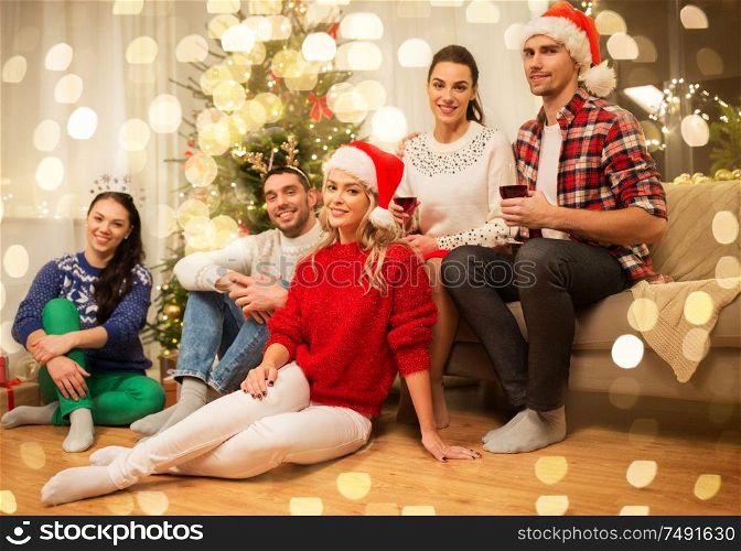 celebration and holidays concept - happy friends with glasses celebrating christmas at home party and drinking red wine. friends celebrating christmas and drinking wine