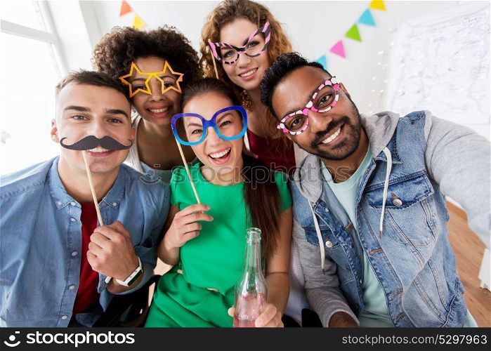 celebration and holidays concept - happy friends with party accessories and non-alcoholic drink having fun at home. happy friends having fun at home party