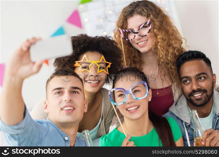 celebration and holidays concept - happy friends with party accessories taking selfie. happy friends taking selfie at party