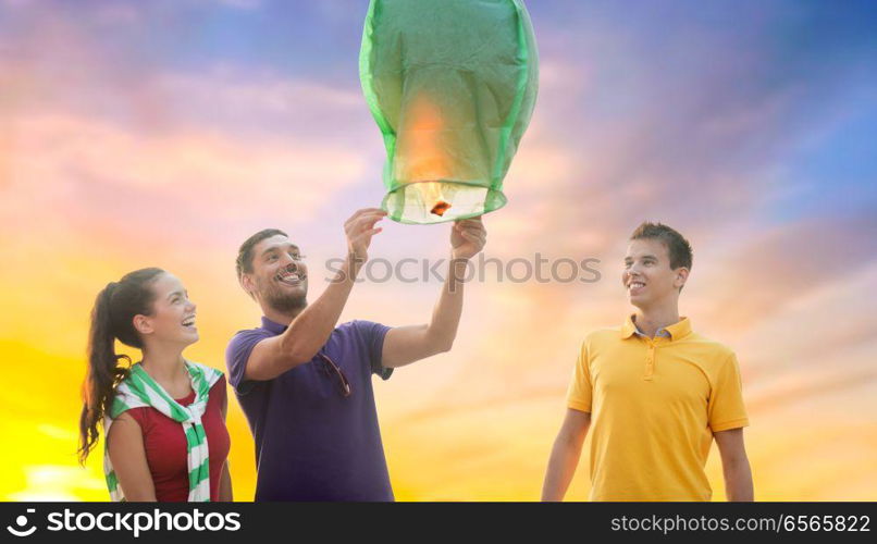 celebration and people concept - group happy friends lighting chinese sky lantern outdoors. happy friends lighting chinese sky lantern