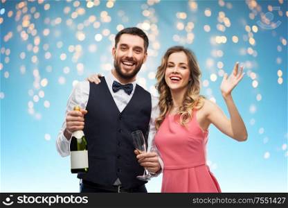 celebration and people concept - happy couple with bottle of champagne and glasses over holiday lights on blue background. happy couple with bottle of champagne and glasses