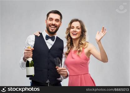 celebration and people concept - happy couple with bottle of champagne and glasses over grey background. happy couple with bottle of champagne and glasses