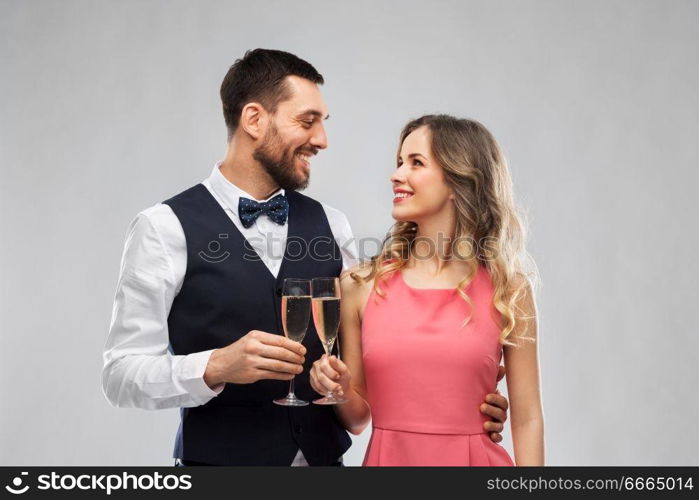 celebration and people concept - happy couple with champagne glasses toasting over grey background. happy couple with champagne glasses toasting