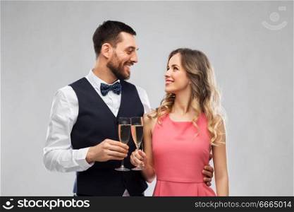 celebration and people concept - happy couple with champagne glasses toasting over grey background. happy couple with champagne glasses toasting
