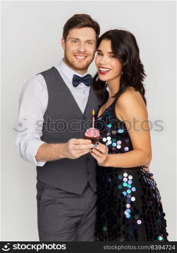 celebration, anniversary and holidays concept - happy couple with cupcake at birthday party. happy couple with cupcake at birthday party