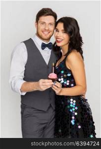 celebration, anniversary and holidays concept - happy couple with cupcake at birthday party. happy couple with cupcake at birthday party