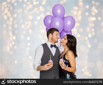 celebration, anniversary and holidays concept - happy couple with ultra violet balloons and cupcakes at birthday party over festive lights background. happy couple with balloons and cupcakes at party