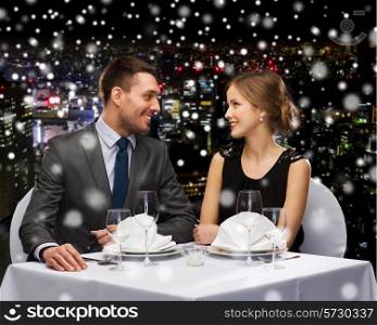 celebration, christmas, holidays and people concept - smiling couple at restaurant over snowy night city background