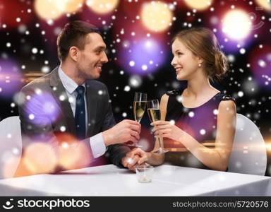 celebration, christmas, holidays and people concept - smiling couple clinking glasses of sparkling wine at restaurant over night lights background