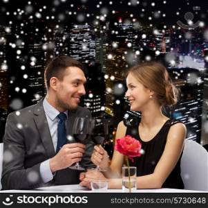 celebration, christmas, holidays and people concept - smiling couple clinking glasses of red wine at restaurant over snowy night city background