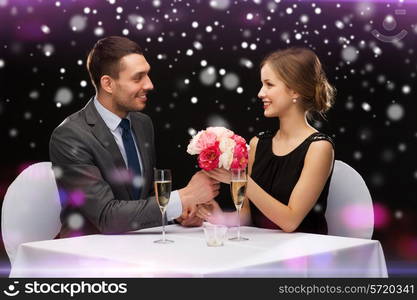 celebration, christmas, holidays and people concept - smiling couple with champagne and flowers at restaurant over night lights background