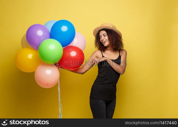 Celebration Concept - Close up Portrait happy young beautiful african woman in black t-shirt smiling with colorful party balloon. Yellow Pastel studio Background.. Celebration Concept - Close up Portrait happy young beautiful african woman in black t-shirt smiling with colorful party balloon. Yellow Pastel studio Background