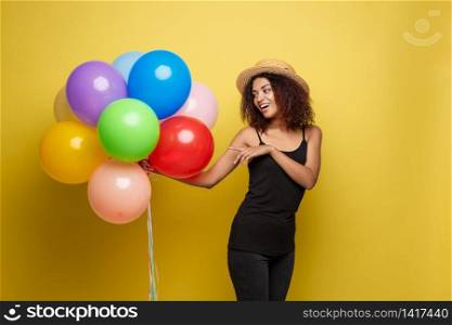 Celebration Concept - Close up Portrait happy young beautiful african woman in black t-shirt smiling with colorful party balloon. Yellow Pastel studio Background.. Celebration Concept - Close up Portrait happy young beautiful african woman in black t-shirt smiling with colorful party balloon. Yellow Pastel studio Background