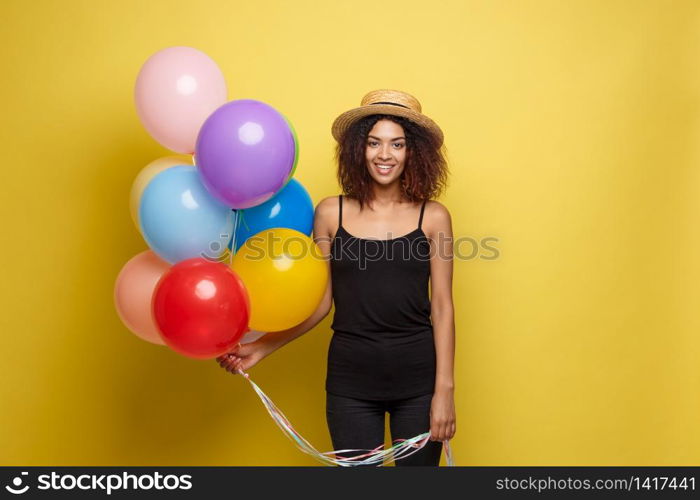 Celebration Concept - Close up Portrait happy young beautiful african woman in black t-shirt smiling with colorful party balloon. Yellow Pastel studio Background.. Celebration Concept - Close up Portrait happy young beautiful african woman in black t-shirt smiling with colorful party balloon. Yellow Pastel studio Background