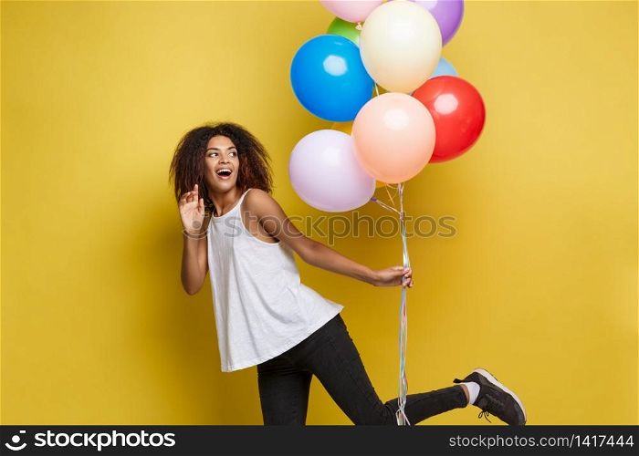 Celebration Concept - Close up Portrait happy young beautiful african woman with white t-shirt running with colorful party balloon. Yellow Pastel studio Background.. Celebration Concept - Close up Portrait happy young beautiful african woman with white t-shirt running with colorful party balloon. Yellow Pastel studio Background