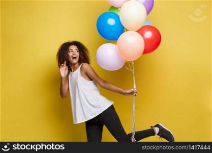Celebration Concept - Close up Portrait happy young beautiful african woman with white t-shirt running with colorful party balloon. Yellow Pastel studio Background.. Celebration Concept - Close up Portrait happy young beautiful african woman with white t-shirt running with colorful party balloon. Yellow Pastel studio Background