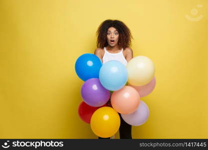 Celebration Concept - Close up Portrait happy young beautiful african woman with white t-shirt smiling with colorful party balloon. Yellow Pastel studio Background.. Celebration Concept - Close up Portrait happy young beautiful african woman with white t-shirt smiling with colorful party balloon. Yellow Pastel studio Background