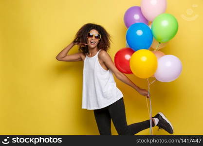 Celebration Concept - Close up Portrait happy young beautiful african woman with white t-shirt running with colorful party balloon. Yellow Pastel studio Background.. Celebration Concept - Close up Portrait happy young beautiful african woman with white t-shirt running with colorful party balloon. Yellow Pastel studio Background