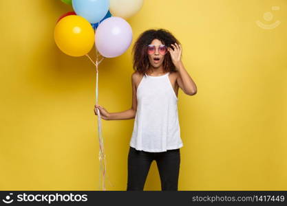 Celebration Concept - Close up Portrait happy young beautiful african woman with white t-shirt smiling with colorful party balloon. Yellow Pastel studio Background.. Celebration Concept - Close up Portrait happy young beautiful african woman with white t-shirt smiling with colorful party balloon. Yellow Pastel studio Background