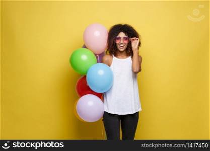 Celebration Concept - Close up Portrait happy young beautiful african woman with white t-shirt smiling with colorful party balloon. Yellow Pastel studio Background.. Celebration Concept - Close up Portrait happy young beautiful african woman with white t-shirt smiling with colorful party balloon. Yellow Pastel studio Background