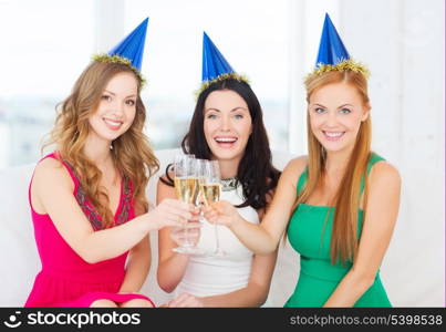celebration, drinks, friends, bachelorette party, birthday concept - three smiling women wearing blue hats with champagne glasses
