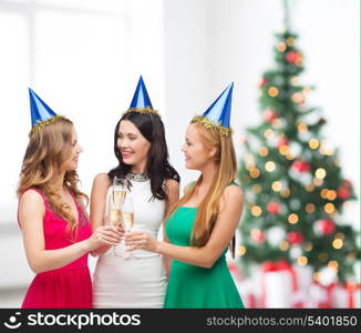 celebration, drinks, friends, bachelorette party, birthday concept - three smiling women wearing blue hats with champagne glasses