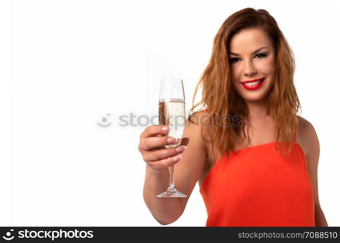 Celebration event concept - young and attractive woman in an orange dress with perfect fingernails holds a glass of champagne or wine and smiling on a white background (copy space).