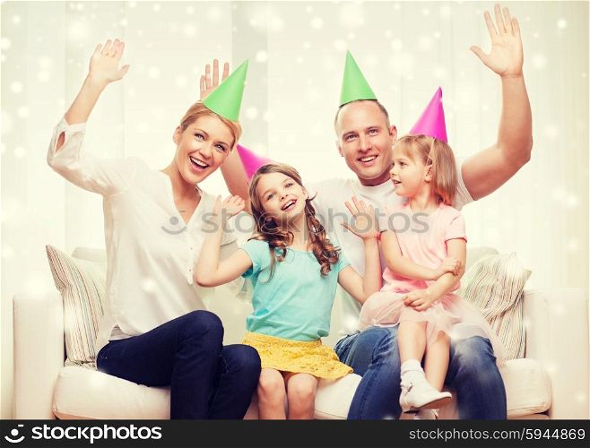 celebration, family, holidays, gesture and people concept - happy family with two kids in party hats waving hands at home