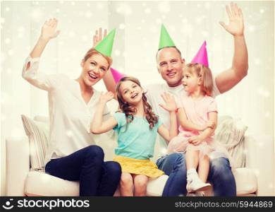 celebration, family, holidays, gesture and people concept - happy family with two kids in party hats waving hands at home