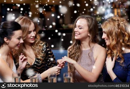 celebration, friends, bachelorette party and holidays concept - happy woman showing engagement ring to her friends with champagne glasses at night club
