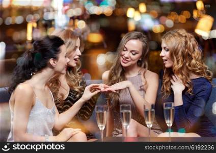 celebration, friends, bachelorette party and holidays concept - happy woman showing engagement ring to her friends with champagne glasses at night club
