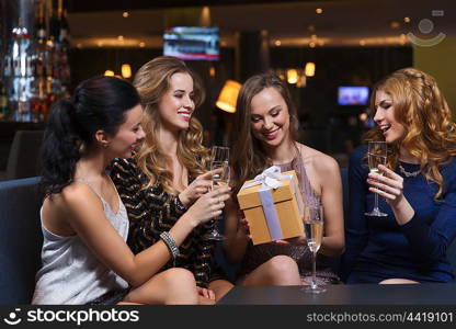 celebration, friends, bachelorette party, birthday and holidays concept - happy women with champagne glasses and gift box at night club